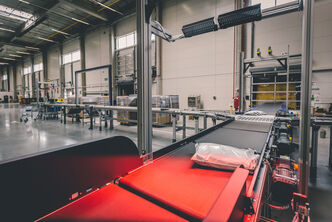An arvato warehouse sorting system with a parcel on a conveyer belt with light barrier