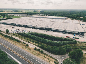 Luftaufnahme einer kompletten Logistikanlage mit Solarpaneelen für Nachhaltigkeit auf dem Dach