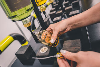 An arvato employee bottling perfume in a flacon as value-added service