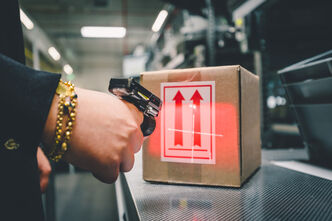An Arvato employee scans a package with a single finger scanner as part of B2B fulfillment