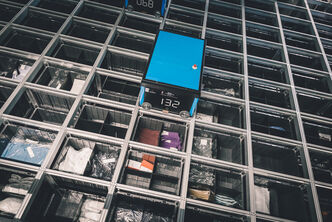 top view of an autostore grid with fashion goods in boxes and a shuttle system performing an inventory