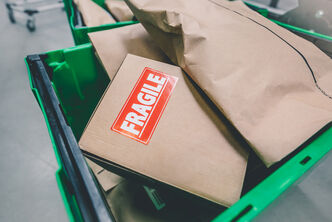 Various packages and parcels in a transport box, one of the packages says "Fragile"