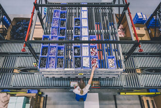 A kanban system with different boxes, an employee picks items for an order from one of these boxes