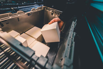 Employee takes a carton out of a box as part of B2C fulfillment.